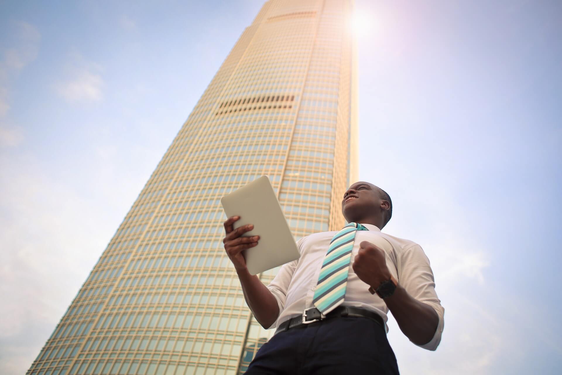man in tie holding report with building in background