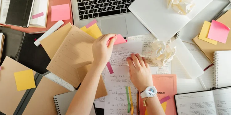 Two hands move paper around a messy desk. Avoid these beginner investment mistakes by cleaning up your best practices.