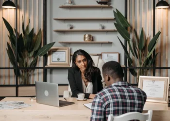 A man and woman sit across a desk from each other, looking at paperwork. Our estate planning guide can help your process.