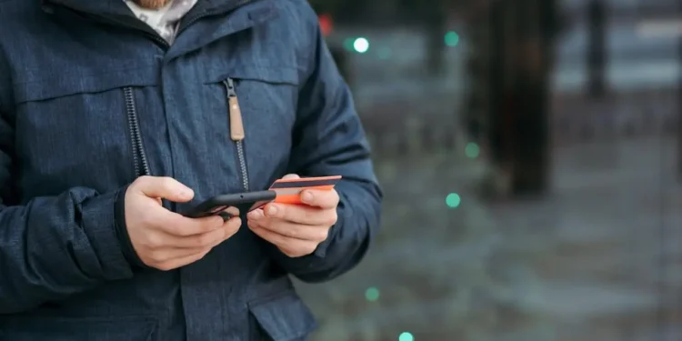 a man holding a phone and a credit card
