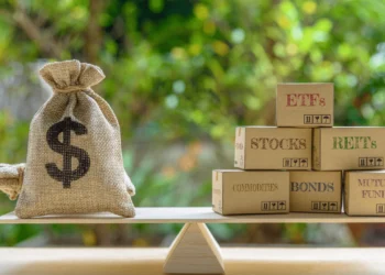 Bag of cash sits on a balanced fulcrum with blocks representing investment diversification options written on them.