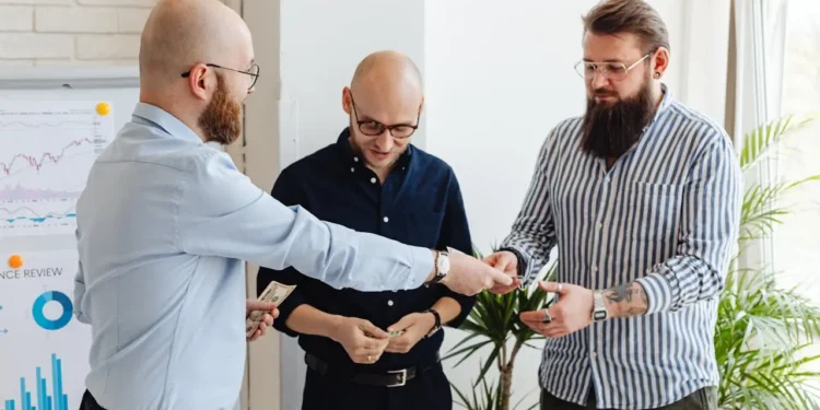 Three men stand together, handing each other money. Is peer to peer lending a good option for you?