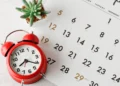 A red alarm clock sits on a white calendar. Target-date funds can help you set it and forget it.