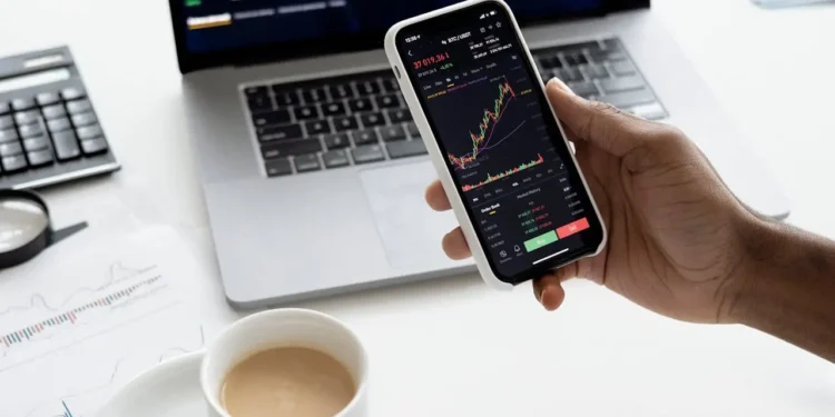 Hand holds phone with investing app on screen