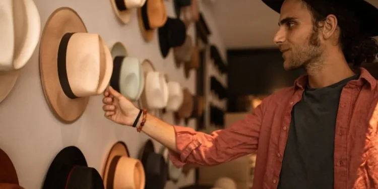 a man touches a hat on a wall - conscious spending means thinking about what you buy before you buy
