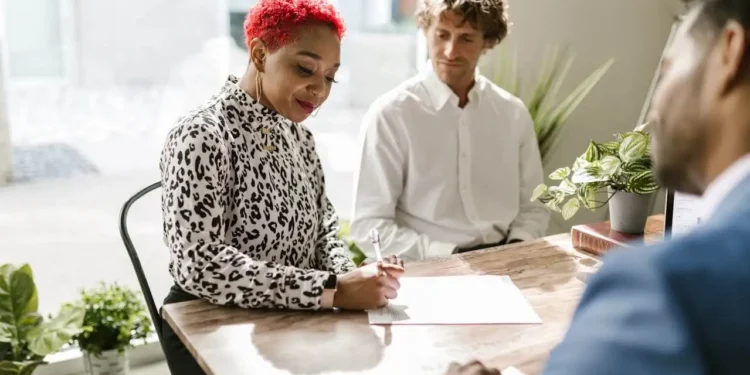 A woman is making a will with two men present in a bright office.