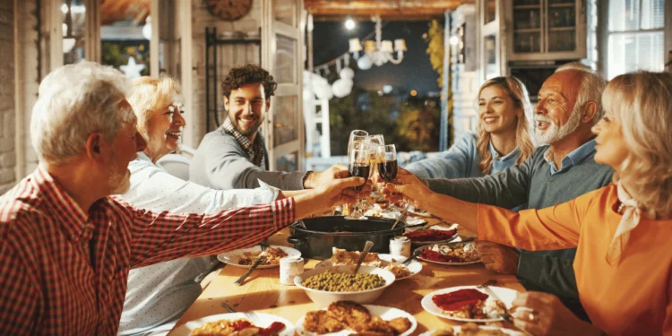 A family celebrates around a dinner table covered in food. Setting financial boundaries with your family or friends doesn't have to feel like a chore.