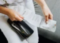 A hand holds a long receipt and a black wallet before they submit to Receipt Hog.