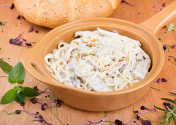 An orange skillet filled with chicken alfredo pasta bake.
