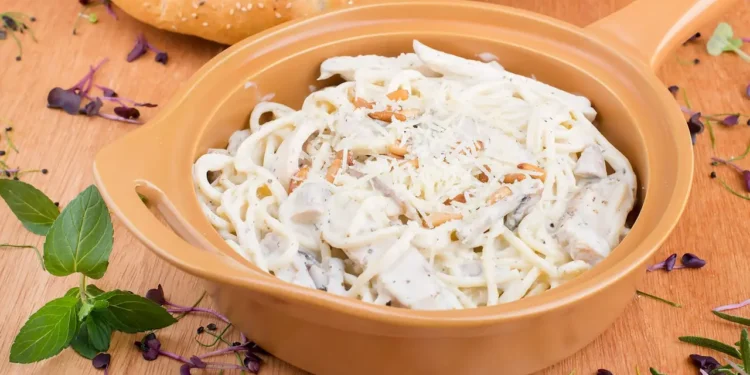 An orange skillet filled with chicken alfredo pasta bake.