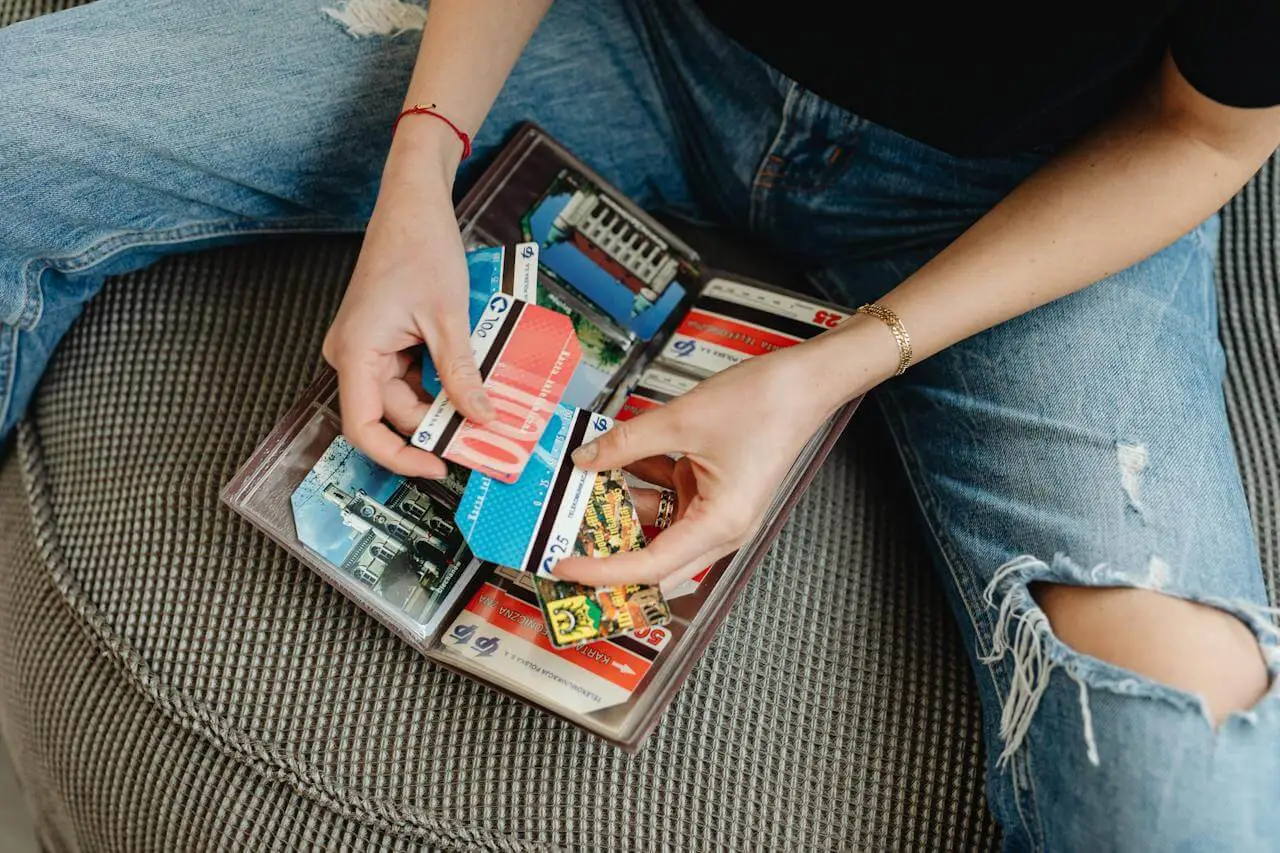 A person sits on a couch going through the cards in their wallet. Comparing cash back vs travel rewards.