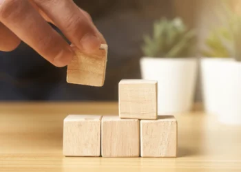 Hand stacks small wooden blocks on a table.