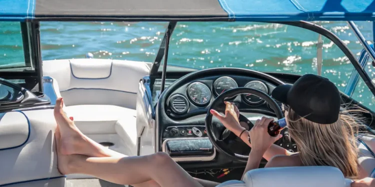 Woman in black cap lounges at the wheel of a boat. Lifestyle creep sneaks up on you.