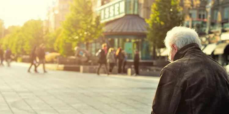 A senior man sits on a sunny bench in a town square. Does old school retirement advice still apply?