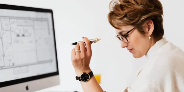 a woman holding a pen in front of a computer - is a line of credit better than a credit card?