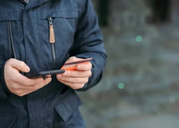 Someone holds a credit card in one hand and a phone in the other. A balance transfer card can save you a bundle on interest.