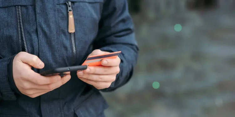 Someone holds a credit card in one hand and a phone in the other. A balance transfer card can save you a bundle on interest.