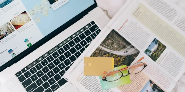 An open laptop with travel rewards credit cards on top of an open magazine.