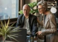 An older man and woman look at a computer screen together. Working after retirement can be the most fun you've had at a job!