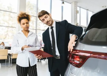 A woman stands in a car dealership, listening to a salesperson.