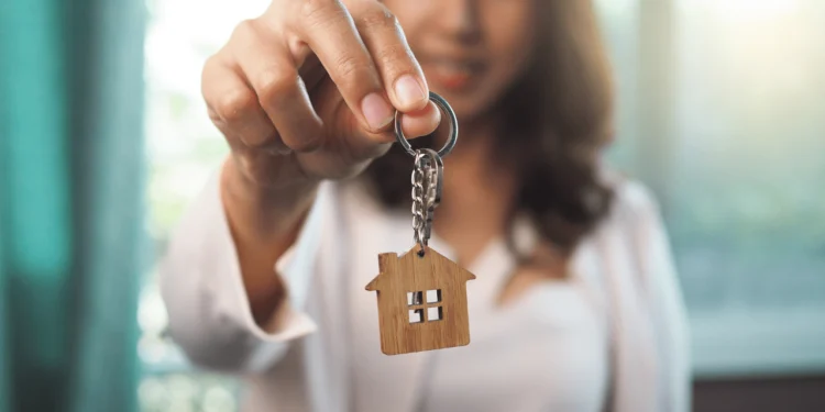 A woman holds a set of keys with a house shaped charm on it. What you need to know when you buy a house.