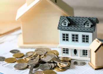 A miniature of a house next to a pile of coins. Down payment assistance can help you purchase your dream home.