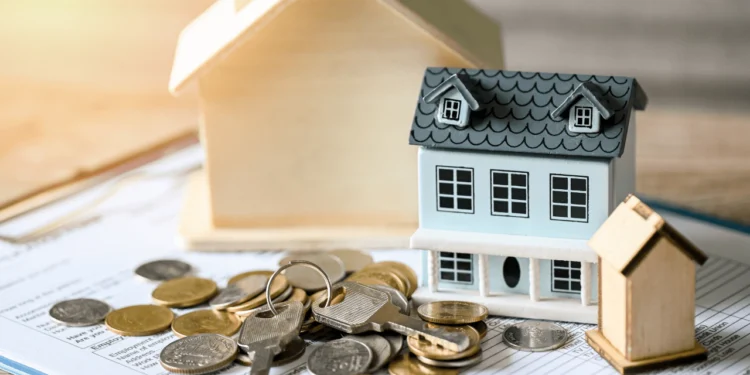 A miniature of a house next to a pile of coins. Down payment assistance can help you purchase your dream home.