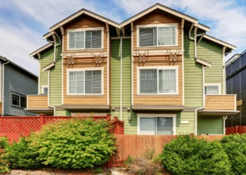 A four plex house with green siding. Multi family homes are a great way to start house hacking.