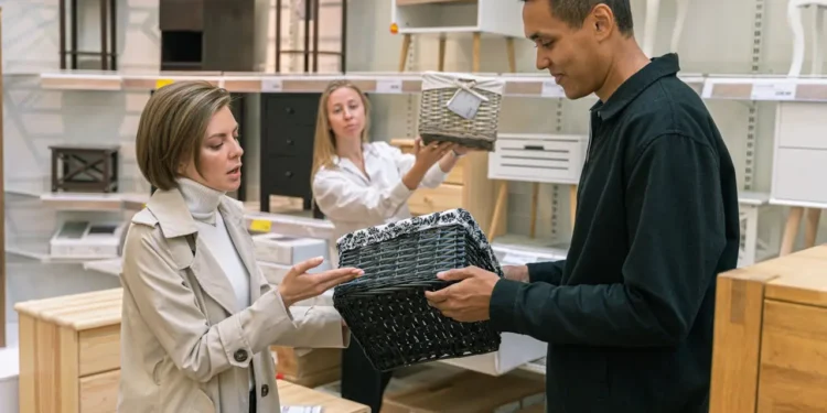 People comparing prices on baskets at a store. Being a cheapskate can cost you in the long run.