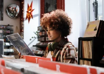 A woman wearing headphones looks at vinyl in a store. Making frugal mindset shifts will change your entire outlook.