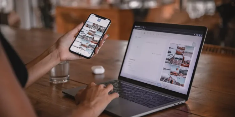 Someone holds a phone up in front of an open laptop. We found six budgeting apps to help you manage your finances.