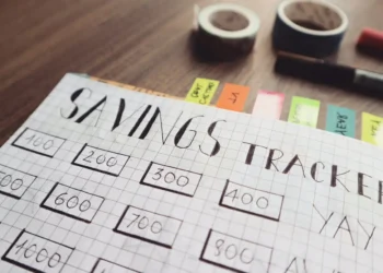A planner sits on a table and the title says Savings Tracking. Using financial motivation hacks can help you stay on track for your goals.