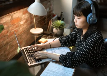 A woman wearing headphones types on a laptop. If you want to improve your resume, here are some tips.