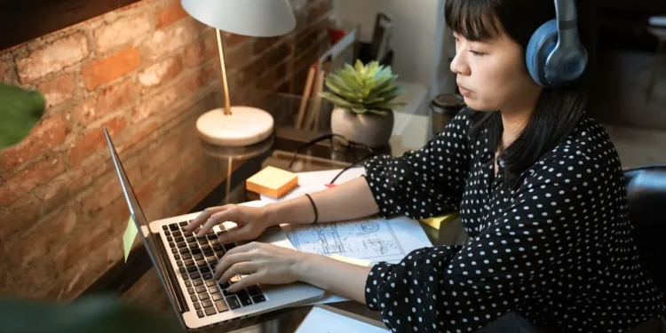 A woman wearing headphones types on a laptop. If you want to improve your resume, here are some tips.