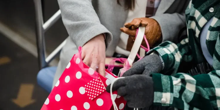 Two people hold colorful gift and shopping bags. Asking yourself mindful questions before Black Friday shopping can help your bottom line.