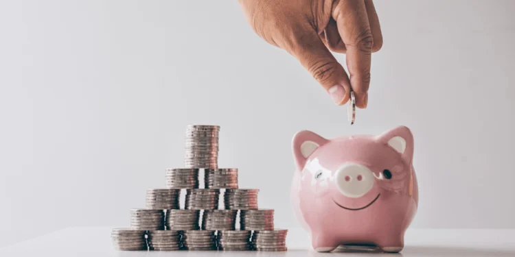 A pyramid made of coins and a hand putting another coin in a pink piggy bank. Is Bank the Rest worth it?