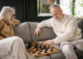 A senior couple sits on a couch playing chess. Planning ahead for retirement expenses can save you money and peace of mind.