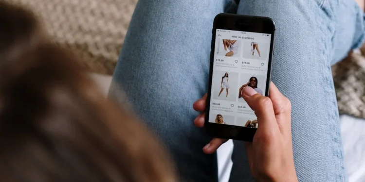 Woman holds phone while she online shops.
