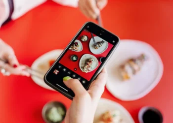 Hand holds a phone with food on the screen. The best restaurant apps save you money and get you perks.