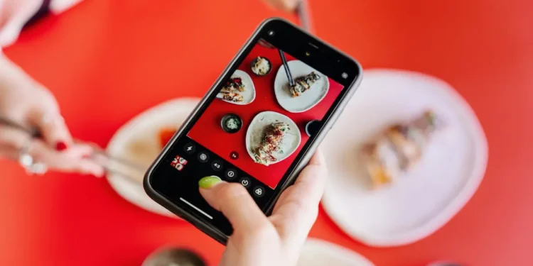 Hand holds a phone with food on the screen. The best restaurant apps save you money and get you perks.
