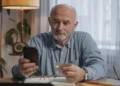 Solo ager senior man looks at phone.