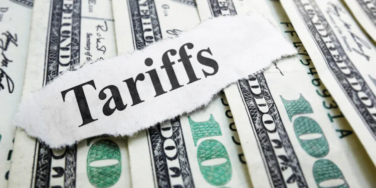 A paper that says 'tariffs' on a pile of US $100 bills