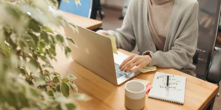 Woman sits at a desk working on a computer. Valuable email lists can save you big time.