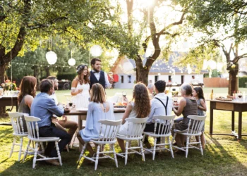 A small wedding party sits at a table in a park, keeping wedding costs low.