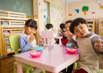 Group of young kids eats snacks at a daycare. Childcare costs are on the rise.