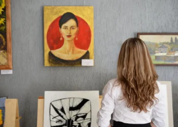 Woman stands in front of a wall of art. Free museum access is a loyalty card perk you could be missing out on.