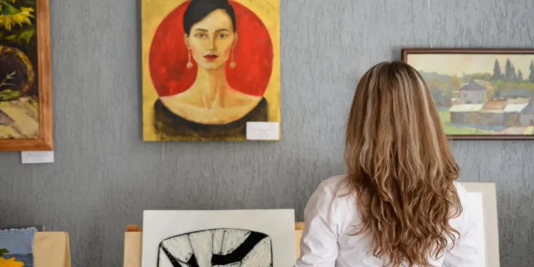 Woman stands in front of a wall of art. Free museum access is a loyalty card perk you could be missing out on.