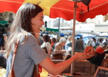 A woman buys something at a farmers market, a budget friendly summer activity.