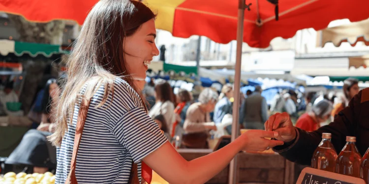 A woman buys something at a farmers market, a budget friendly summer activity.