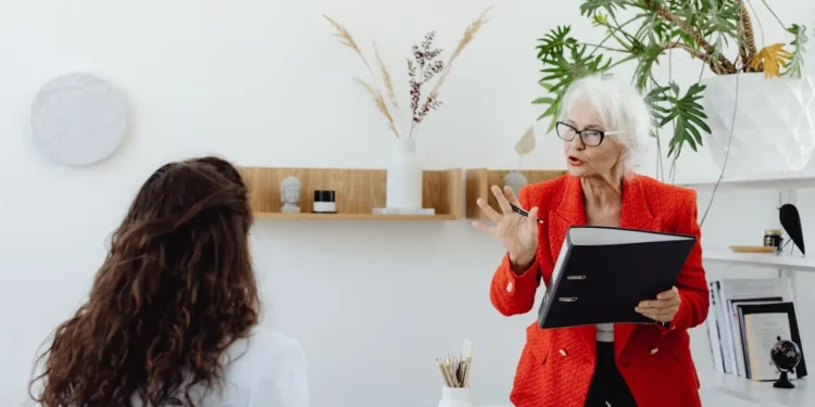 An older woman talks to a younger one in an office. Consulting after retirement can be an exciting next step!